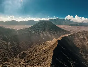 Day Sky Prints: Cinematic shot aerial view of Mount Bromo crater edge with active volcano smoke in East Java