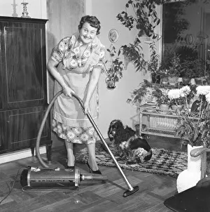 Floors Prints: Cleaning day in the 1950s. A housewife is vacuuming the floor using the latest model from Electrolux