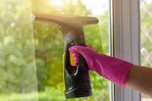 Cleaning windows with portable professional vacuum cleaner. Hand in protective glove