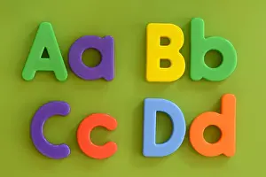 Toys Prints: Close up of Aa Bb Cc Dd in colorful plastic letter toys on green background