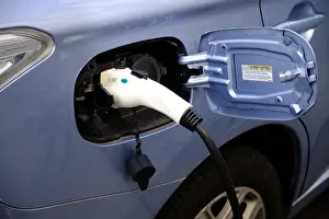 Open Door Prints: Close up of EV cable electric car charging plug connected to a blue car