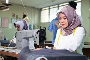 Veil Prints: close up female tailor in hijab using a sewing machine while workin