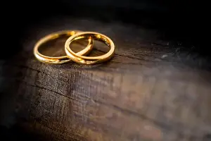 Bokeh Background Prints: Close up of two golden wedding rings lying on the edge of an ancient and weathered wooden table