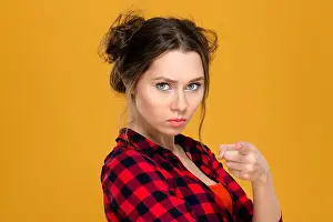 Young Girl Prints: Close up portrait of angry irritated young woman in plaid shirt pointing on you over yellow background