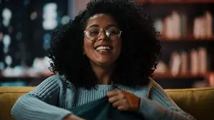 Latina Prints: Close Up Portrait of a Happy Laughing Young Latina with Afro Hair and Glasses Posing for Camera at Home