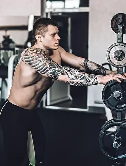 Bodybuilder Prints: close up. male bodybuilder with a tattoo on his arm standing in the gym