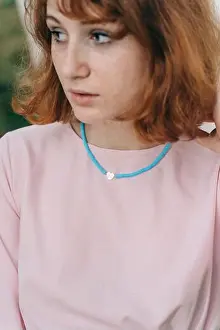 Redhead Prints: Close-up portrait of a young red-haired woman wearing a turquoise beaded necklace with a white heart-shaped pendant