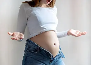 Facial Expression Prints: Close-up of a pregnant woman's bloated belly unable to button up her pants