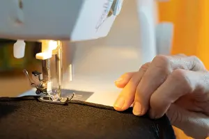 Sewing Machine Prints: Close-up shot of hands carefully guiding fabric under the needle of a sewing machine
