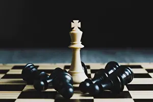 Chess Prints: Close-up of a white king piece, surrounded by fallen black pieces. Leadership concept