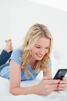 Texting Prints: Close up, woman lying on a bed using her smartphone and smiling