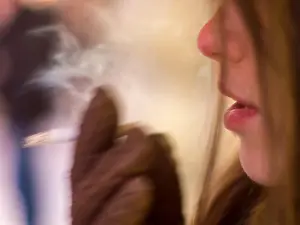 Nicotine Prints: Close-up of a young girl wearing gloves that smokes a cigarette in the winter in the cold on the street