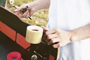 Smart Prints: A close-up of a young guy changes his wheels on his longboard and adjusts the suspension.