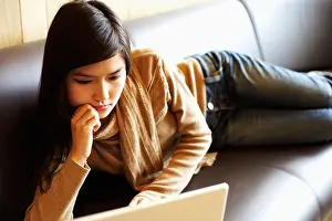 Concentrate Prints: Close-up of a young woman lying on a couch in front of a laptop