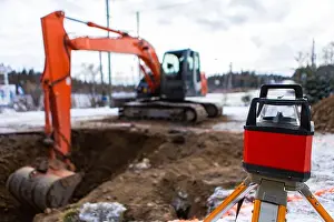 Scoop Prints: A close up view of a laser level with tripod set up on a building site