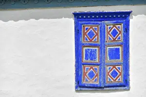Closed vintage blue and red window on white wall of old traditional house in romania