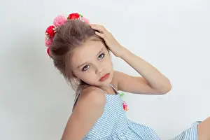 Closeup beautiful little girl wreath of flowers on head posing in studio hand on head isolated white grey background