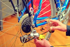 Repairman Prints: Closeup of male hands cleaning and oiling a bicycle chain and gear with oil