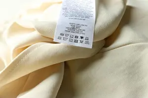 Polyester Prints: Clothing label with care instructions on beige garment, closeup