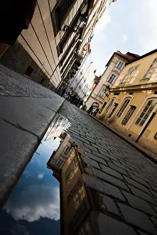 Slavic Prints: cobblestone street in prague with reflection of buildings in a puddle