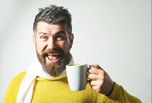 Coffee Cup Prints: Coffee time. Happy bearded man in knitted sweater and scarf drinking cup of tea or coffee in cafe