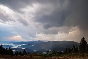 Low Clouds Prints: Cold cloudy rainy weather over low hills covered with spruce evergreen forests in Rhodope Mountains against backdrop of