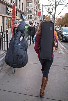 College music students in Boston both carry and wheel their instruments on the sidewalk