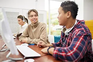 Teens Prints: College students sitting in row and chatting while studying in computer class