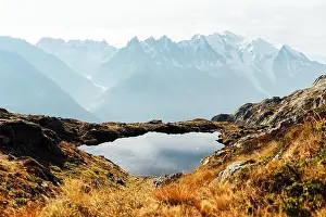 Colourful autumn landscape with Chesery lake (Lac De Cheserys) and snowy Monte Bianco mountains range on background
