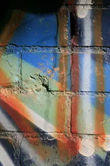 Dilapidated Prints: colourful urban graffiti on old wall surface in sun outdoors