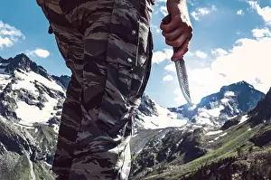 Camo Prints: Combat knife in hand the soldier the commando in the background of snow-capped peaks in the mountains