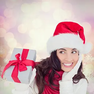 Santa Hat Prints: Composite image of surprised brunette in santa hat holding gift