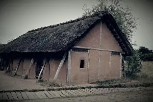 History House Prints: Concrete barn with a thatched rooftop in a rural area under the clear sky