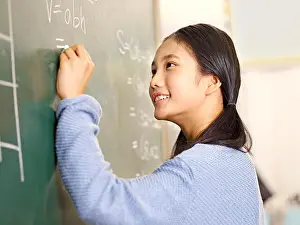 Taiwanese Prints: confident asian elementary school student writing the answer to a geometry problem on blackboard