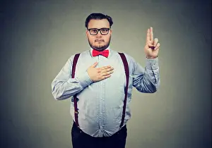 Solemn Prints: Confident serious man in formal outfit holding hand on chest and making promise looking at camera