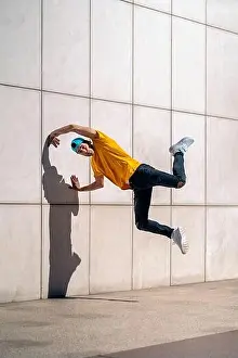 Having Fun Prints: Confident young boy doing break dance dances against white wall in the street