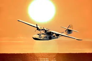 Twin Engine Prints: Consolidated Catalina flying boat at sunset over the sea with large sun
