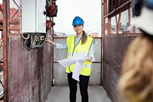 Headwear Prints: Construction manager holding documents while showing machinery in construction elevator