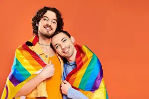 Casual Attire Prints: contented appealing young gay men in cozy attires with rainbow flag on orange backdrop