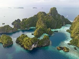 April Collection: Coral reefs surround the dramatic limestone islands that have been uplifted from Raja Ampat's