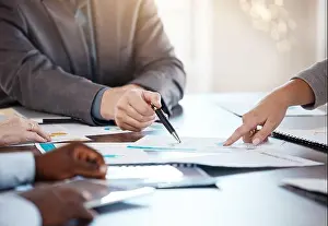 Corporate table, documents and hands in conversation on business analytics data report in office