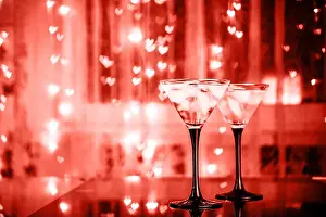 Valentines Day Prints: Couple of cocktail glasses with martini drink with ice on trendy black background with bokeh lights