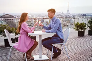 Eiffel Tower Prints: couple drinking champagne in luxury rooftop restaurant in Paris with panoramic view of Eiffel Tower