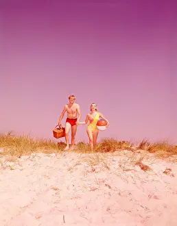 Holding Hands Prints: Couple with picnic basket and ball walking on beach