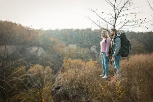 Couple Relationship Prints: Couple of tourists admiring the sunset standing on the edge of a cliff holding hands
