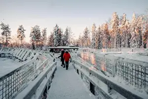 Boreal Prints: Couple walking over snowy footbridge in wildlife park in Ranua, Lapland