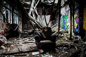 Urban Decay Prints: Crack den, an old armchair sits in the middle of a collapsing building surrounded by needles