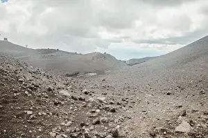 Earthquake Prints: Top of crater Mount Etna volcano, frozen cold lava smokes, thick clouds