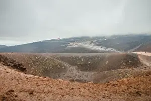 Top of crater Mount Etna volcano, frozen cold lava smokes, thick clouds