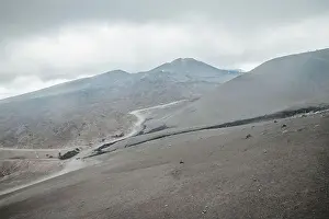 Earthquake Prints: Top of crater Mount Etna volcano, frozen cold lava smokes, thick clouds